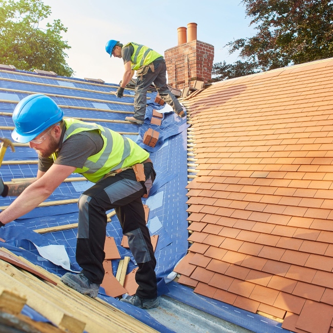 two men in hard hats installing a roof on a home