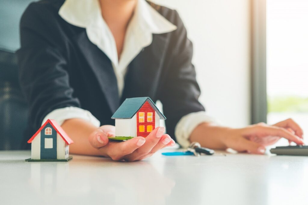 A person holding a miniature house model in their hand